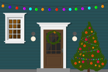 blue house with a door and windows in the evening with a garland for the holiday and christmas tree