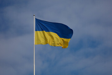 Flag of Ukraine against a blue sky with white clouds