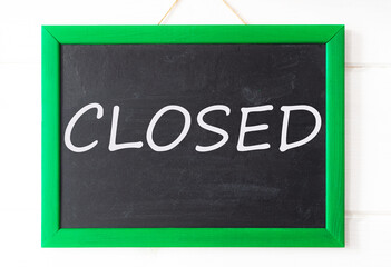 Closed, written in chalk on a black chalkboard in a green frame.