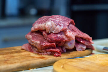 Raw beef sliced meat on wooden cutting board on marbled countertop. Heap of pieces raw beef steakes.