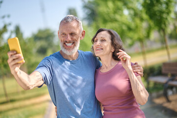 Naklejka premium A happy couple in the park feeling good and making selfie
