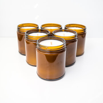 Six amber colored jar candles in a triangle formation 