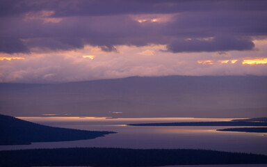 A beautiful mountain landscape with a lake in the distance and low creeping clouds. Autumn mountains of Khibiny in Russia
