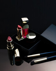 set of cosmetics for a female face and eye makeup in a black craft box on a pink background.