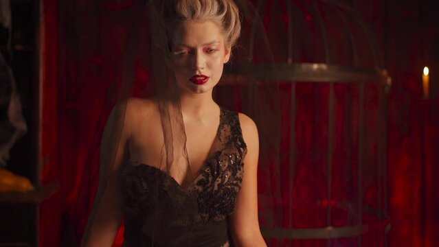 Halloween witch with cauldron. Beautiful young woman flowers in hair conjuring, making witchcraft. Standing spooky dungeon dark room. Enchantress prepare love potion use magic spell. Handheld