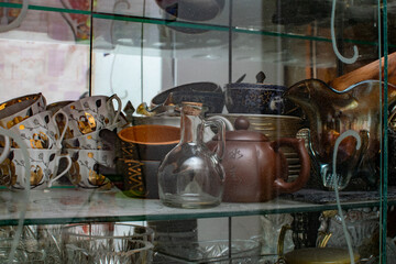 Various crockery under glass in a sideboard, plates and mugs in an old cupboard, a set and set of props for filming and preparing food and drinks, original vessels