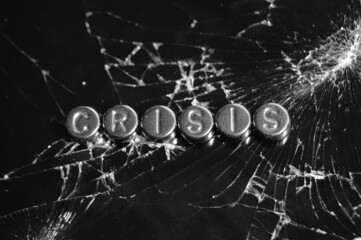The word crisis on broken glass. Abstract photo.
