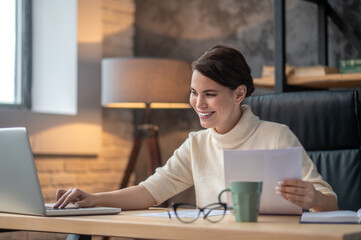A woman sitting at the table in the office and working