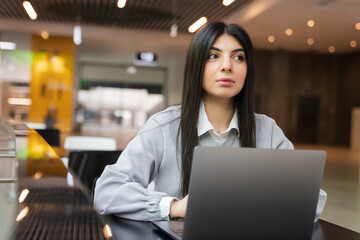 Portrait of a young woman working on a laptop in a cafe