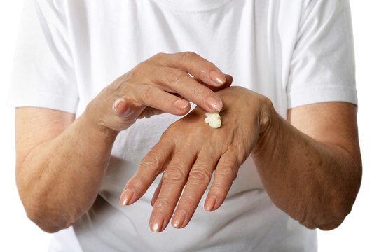 Older Woman Applying Cream On Hands Closeup