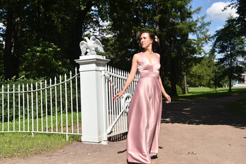 elegant brunette woman in pink dress in the park