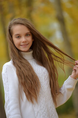 girl brunette child in white sweater in autumn in the park
