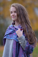brunette girl in autumn in the park in a scarf on her shoulders