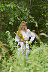 woman in a white slavic shirt among the greenery in summer