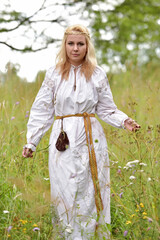woman in a white slavic shirt among the greenery in summer
