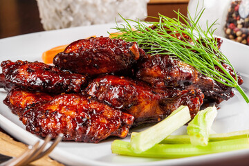 Buffalo chicken wings with crunchy vegetables on a white plate. Close up