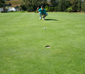 Making this look easy. Shot of a focused young man waiting for the golfball he just hit to go into a hole outside on a golf course.