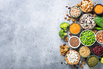 Fototapeta na wymiar Vegan protein source. Legumes, beans, lentils, nuts, broccoli, spinach and seeds. Top view with copy space at gray stone table. Healthy vegetarian food.