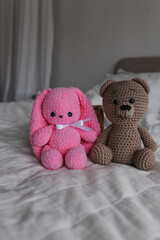 Knitted toy bunny pink and brown bear in a bright room