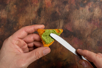 Avocado puree. Spread chopped avocado on a triangle of corn. Healthy vegan food concept. High...