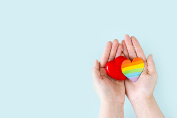 International Day Against Homophobia, Transphobia and Biphobia. May 17. Stop Homophobia. Heart with rainbow LGBT flag in the hands on a blue background. banner or greeting card.