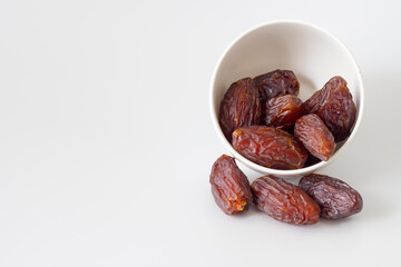 Date fruits spilling from bowl isolated on white background. Ramadan fruit