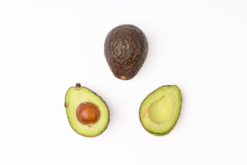 whole and halves of avocado on white background, top view