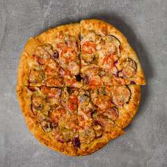pizza with bacon, tomatoes and mushrooms cut into pieces, top view