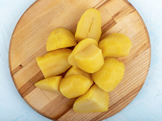 Boiled peeled potatoes on a wooden cutting board.