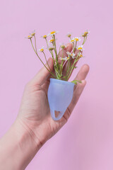 Blue menstrual cup in the palm of a woman's hand.