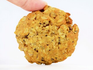 A woman's hand holding homemade multigrain cookie with oatmeal, several kinds of seeds and nuts. Healthy eating concept