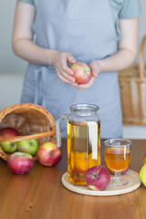 Young woman and fresh homemade organic apple juice or cider on a wooden table in a glass jug
