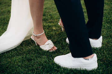 newlyweds stand on the grass, legs close-up