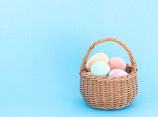 Fototapeta na wymiar Easter concept. Wicker small basket with colorful Easter eggs on a blue background. copy space.