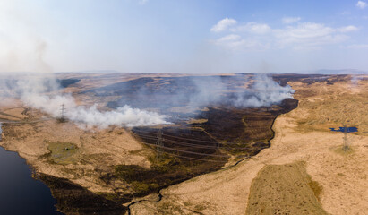 Aerial view of a huge wildfire on high level moorland next to a reservoir (Llangynidr Moors, Wales)