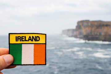 Sign Ireland and Irish flag in focus. Dún Aonghasa and cliffs of Inishmore, Aran islands,...