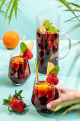 A pitcher filled with summer spanish cocktail sangria and glasses decorated with a pice of apple, strawberry and a pinch of mint.