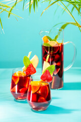 A pitcher filled with summer spanish cocktail sangria and glasses decorated with a pice of apple,...