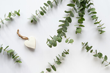 Fresh eucalyptus leaves and twigs. Wooden heart trinket with white enamel and hemp cord. Top view...