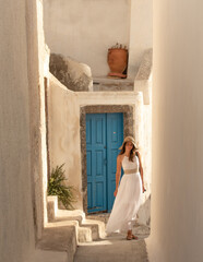 Young beautiful pretty white woman in Oil old town in Santorini greek island in Greece near blue door and white buildings in summer. High quality photo