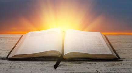 Open Holy Bible on wooden table outdoors