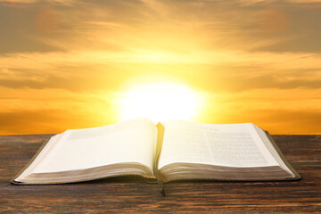 Open Holy Bible on wooden table outdoors
