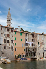 Fototapeta na wymiar View from the sea on the coast of the old town of Rovinj with the facades of houses, the bell tower, Croatia. Vertical photo