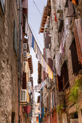 Fototapeta na wymiar Clean laundry drying between stone houses on a narrow street in the old European city of Rovinj, Croatia