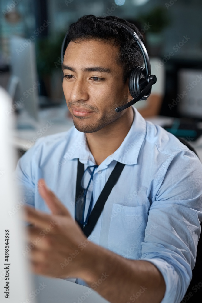 Aufkleber ill walk you through it. shot of a young man using a headset and computer in a modern office.