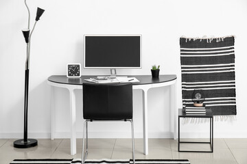 Stylish home workplace with computer near white wall in room