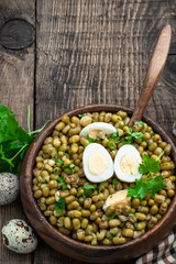 Mung bean salad with quail eggs and olive oil in wooden bowl