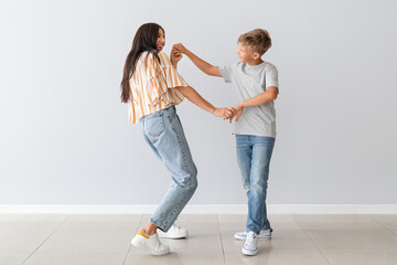 Happy dancing woman and her son on light background