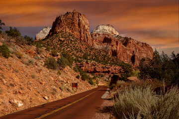 the primary highway through Zion National Park.  Huge red sandstone rocks loom above the road.  The...