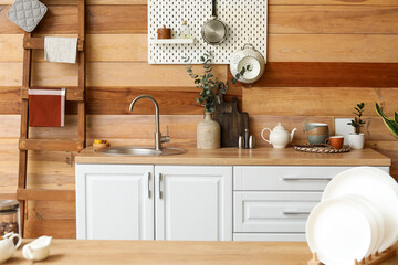 Plates on table and kitchen counter with sink near wooden wall